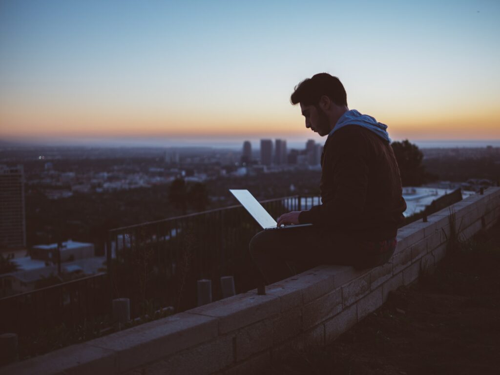 Young employee sitting outside and working from wherever he wants. Workers are allowed to choose their way of working, as long as performance is good.